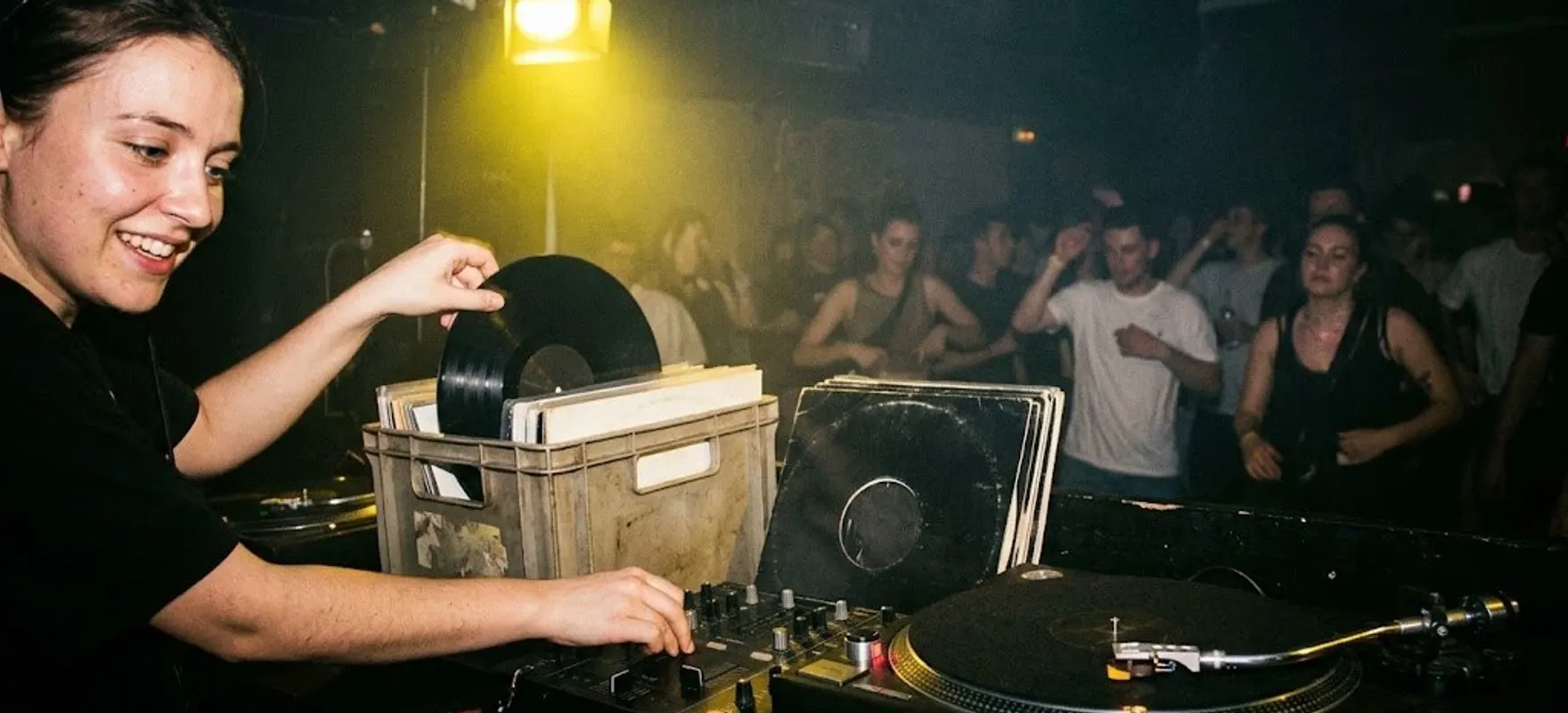 DJ-ka wyciąga płytę winylową ze skrzynki obok gramofonu podczas imprezy