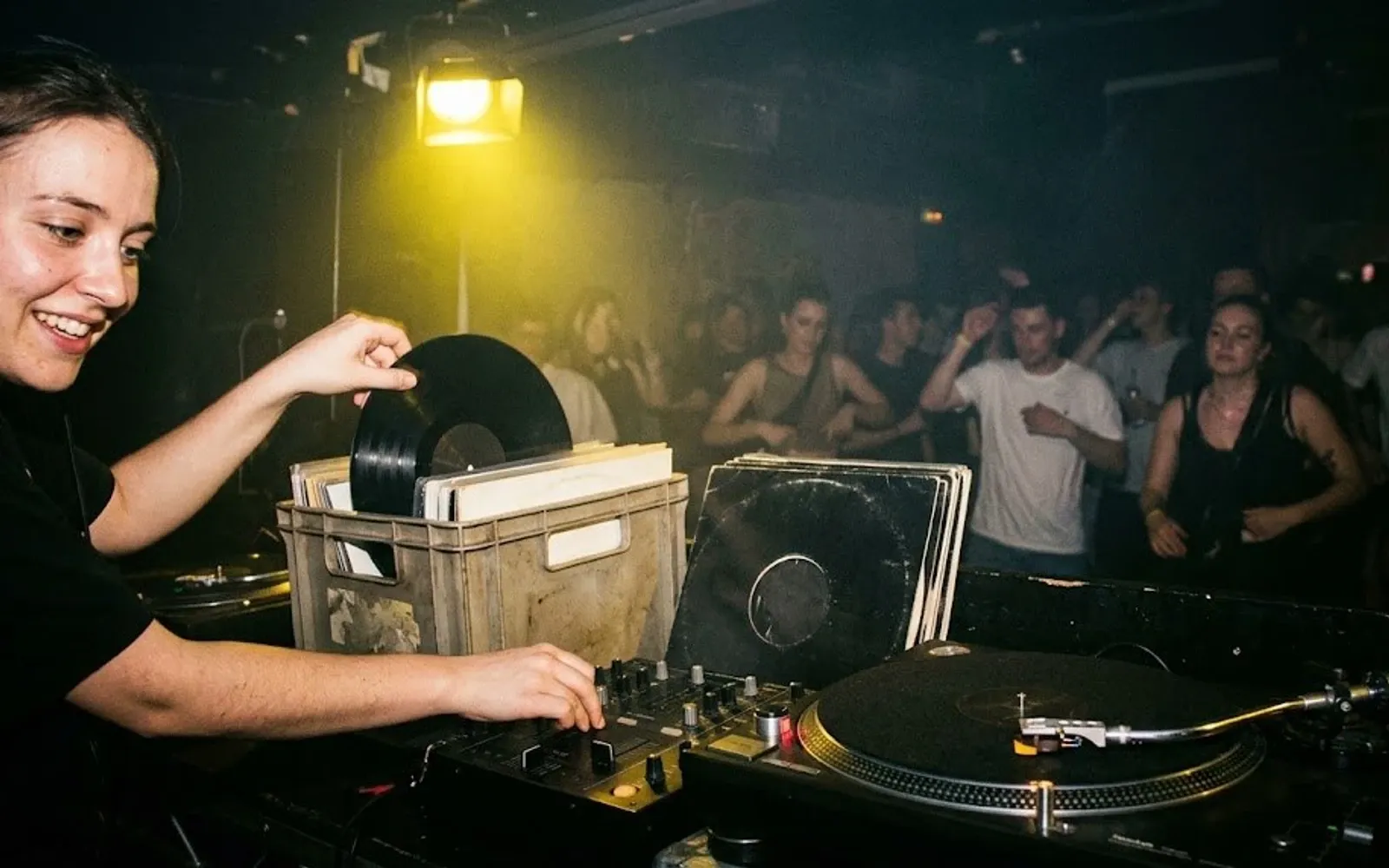 DJ-ka wyciąga płytę winylową ze skrzynki obok gramofonu podczas imprezy